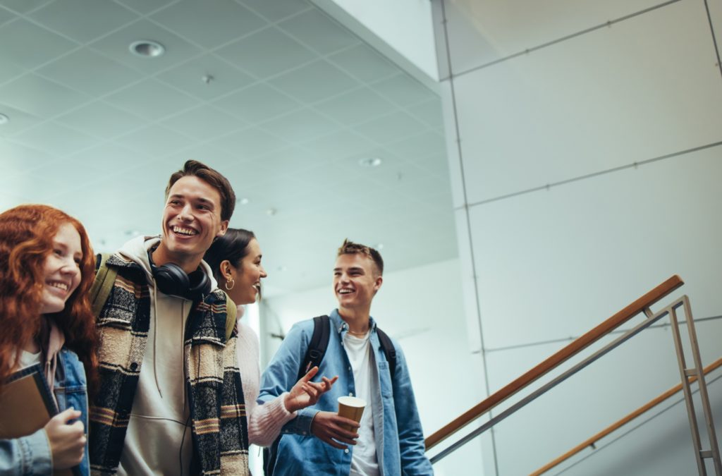 Gruppe von Jugendlichen, lachend, in einem Foyer einer Schule oder Hochschule